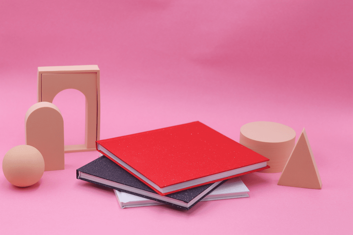 Red, black and white sparkling photobooks stacked on top of each other.